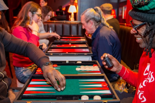 Two black men smiling while they play backgammon